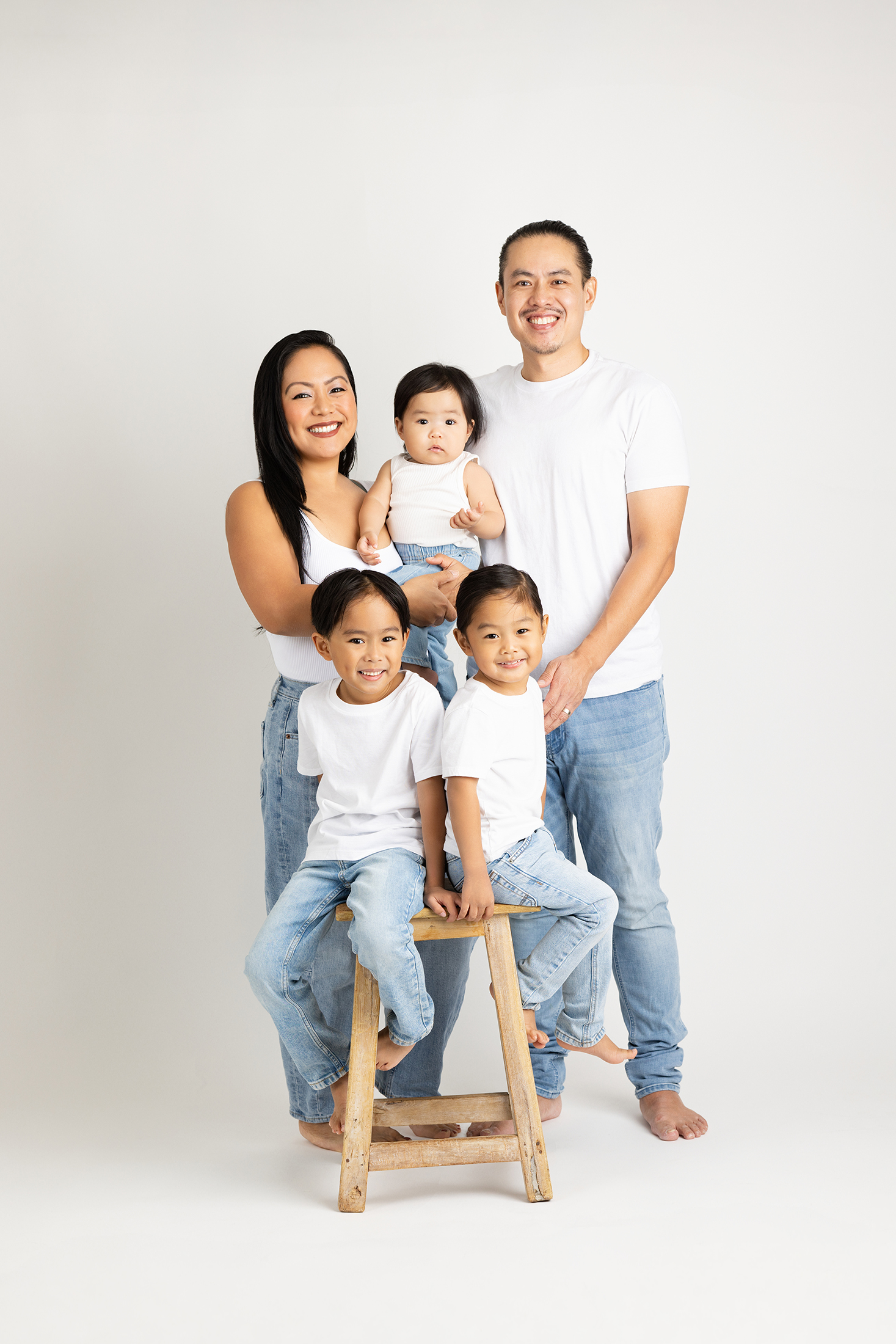 Family of five posing together in front of a white studio background at Lovely Baby Photography in Carlsbad